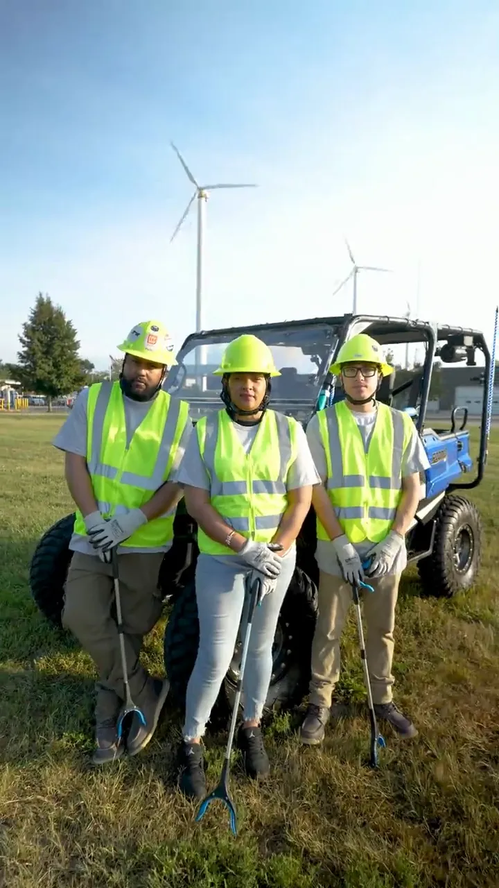 Three Star City Environmental crew members in hard hats and branded high-visibility vests standing at their site vehicle.